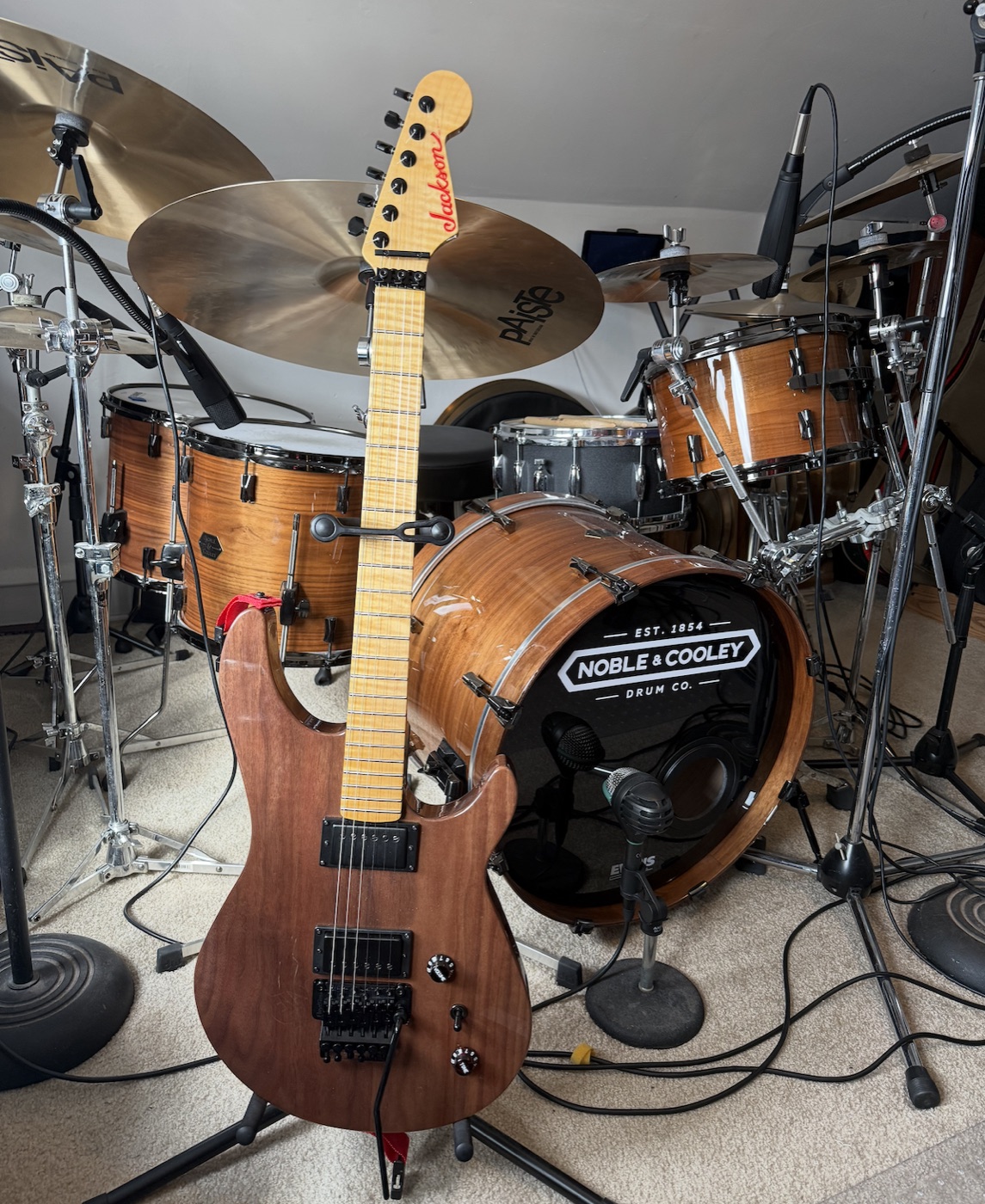 Warmoth walnut custom guitar leaning against the Noble & Cooley drum kit