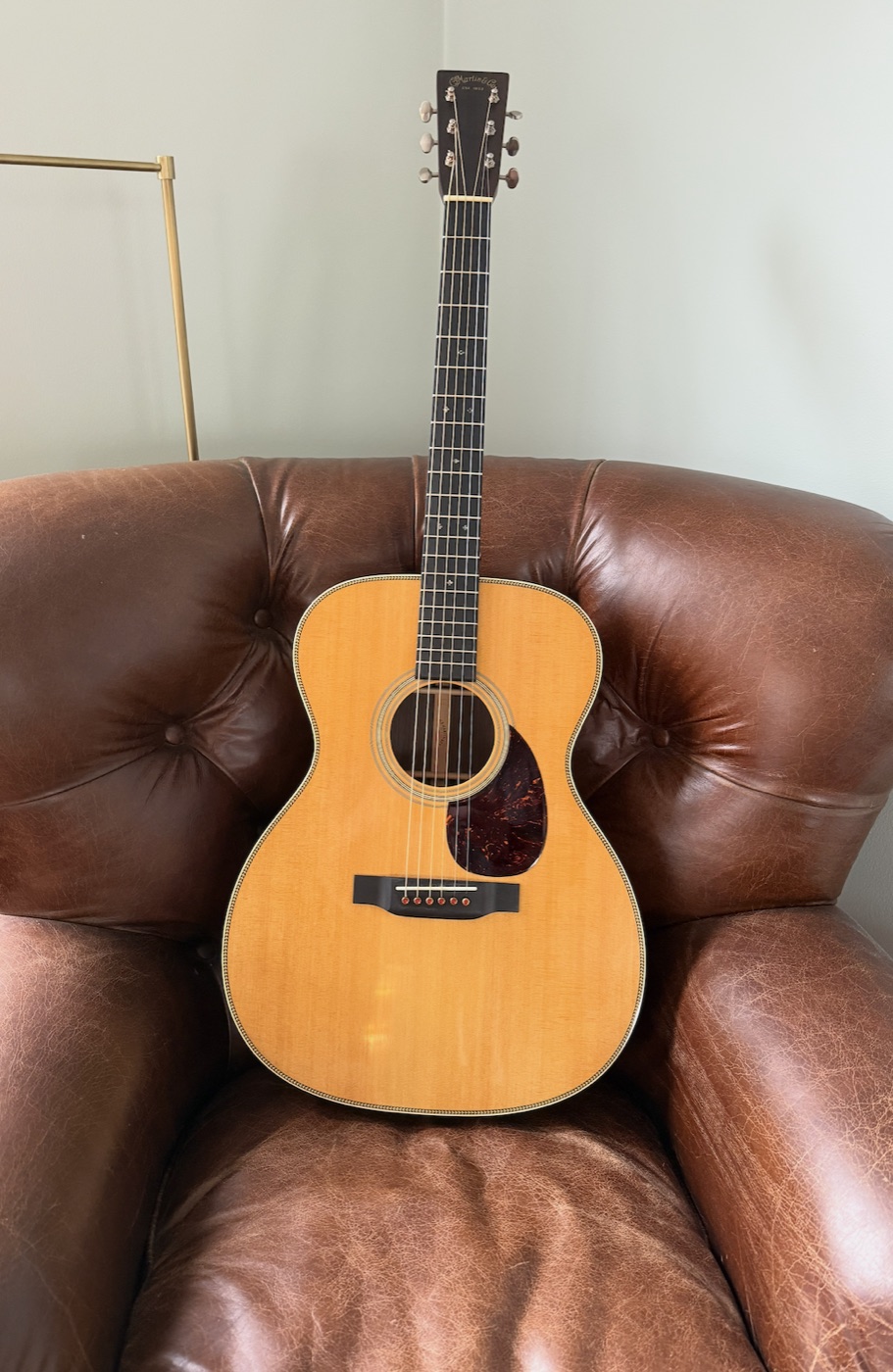 Martin OM-28 acoustic guitar resting on a leather chair