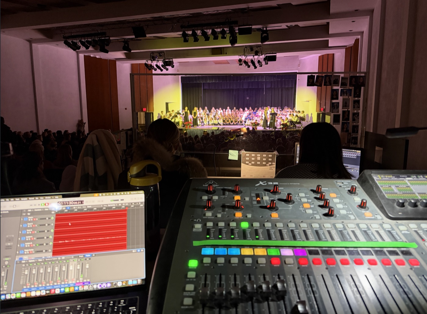 Mixing console at FOH position with orchestra on stage in auditorium