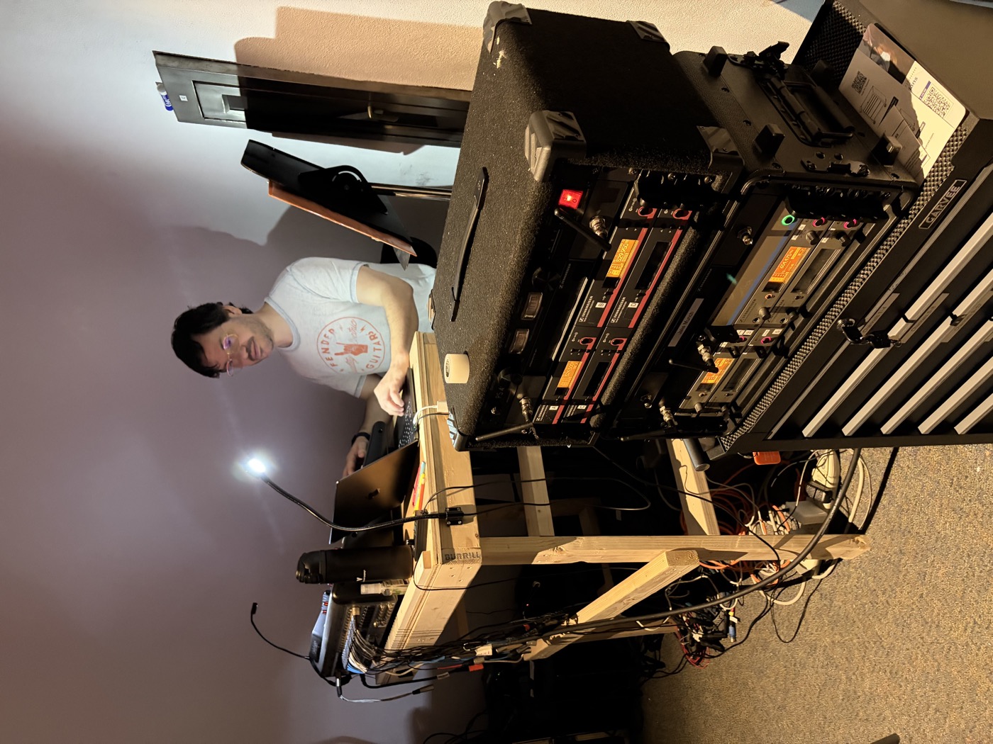 Jake Munch at a laptop workstation with a large RF wireless receiver rack