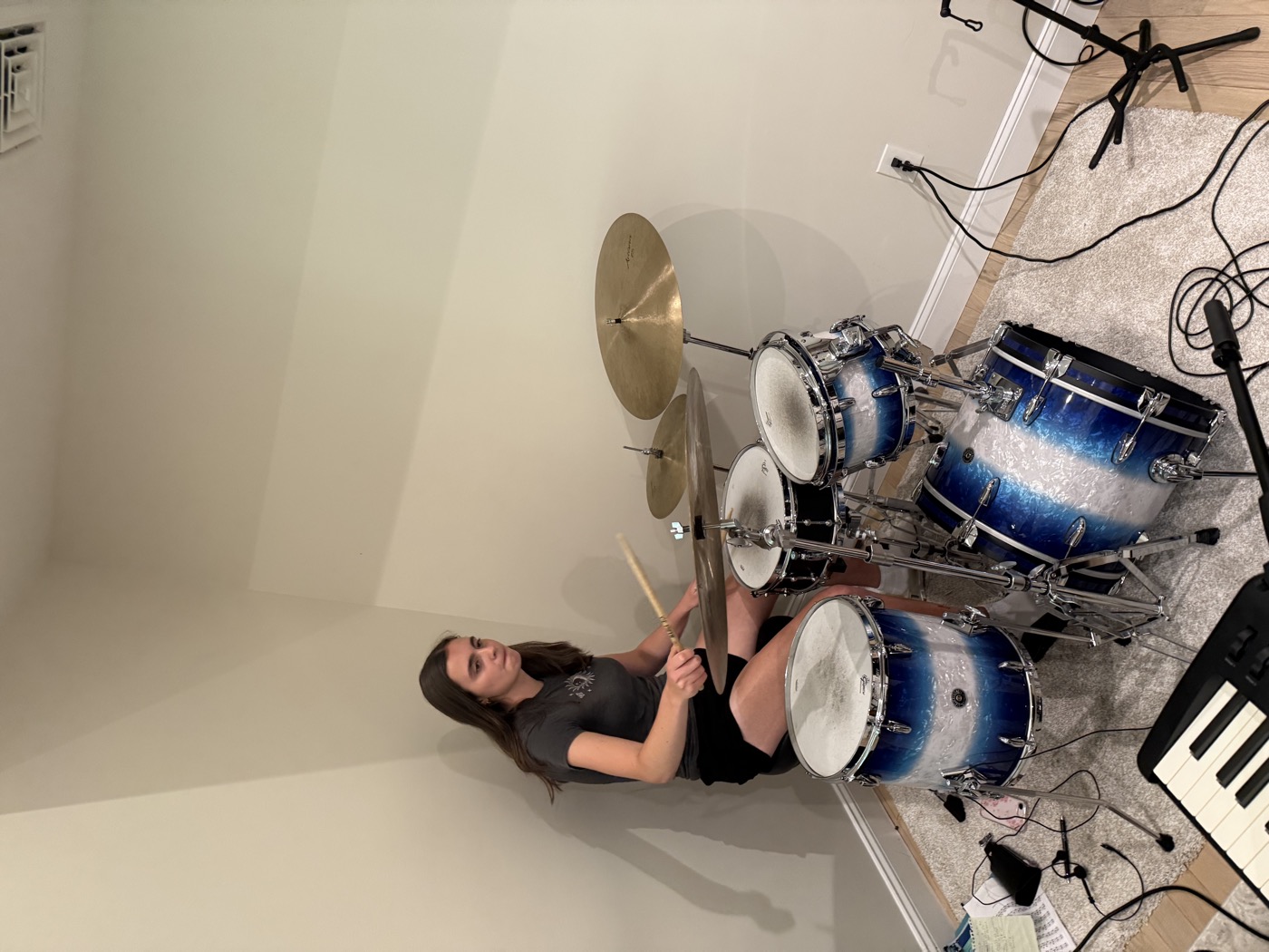 Student playing a blue drumset during an in-person lesson